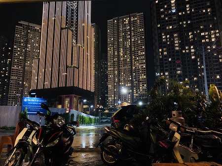 ライトアップされた高層ビル群と手前にバイクが停車したホーチミンの夜景