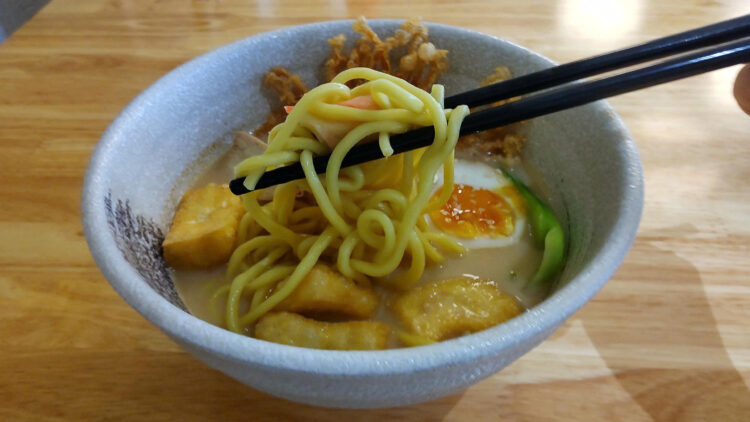 箸で麺をすくっている